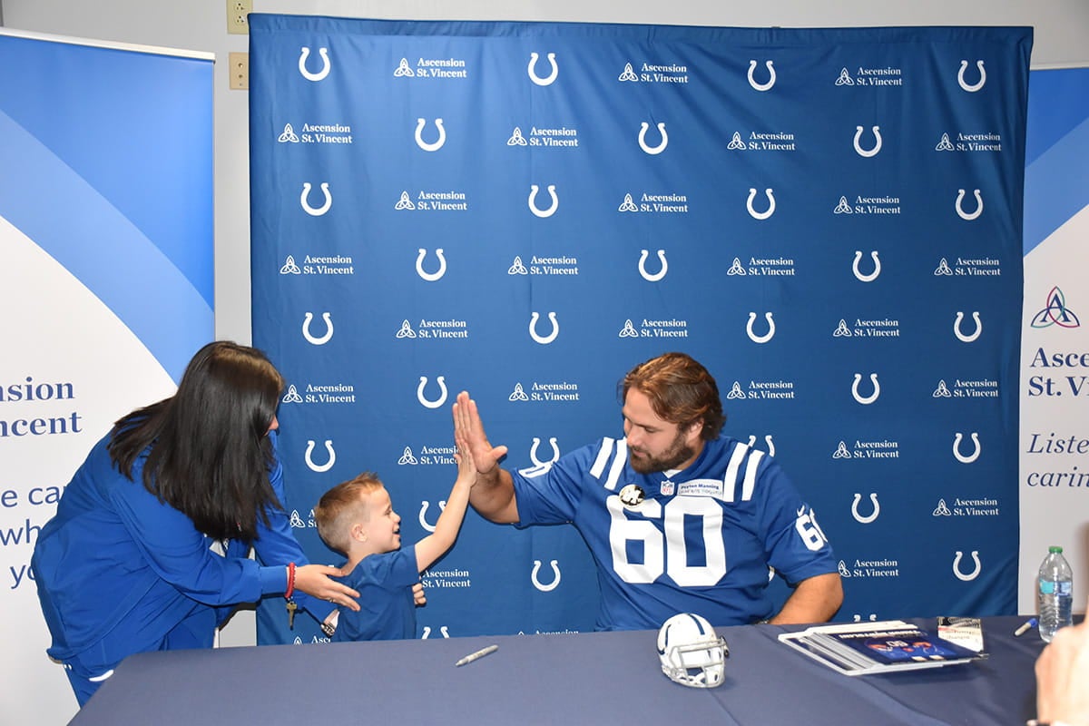 Child high-fives Indianapolis Colts player at Ascension St. Vincent event table