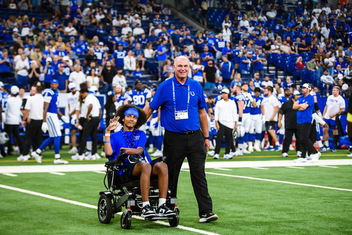 Child in a wheelchair on field with Colts staff during stadium event