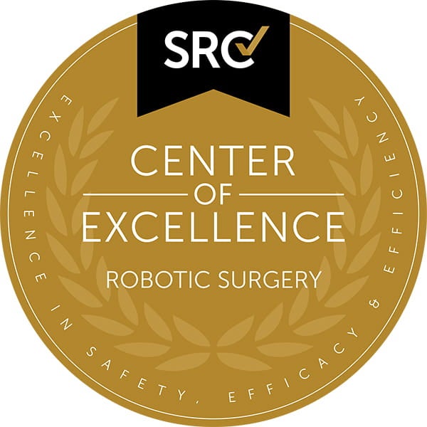 Gold circular seal with laurel wreath design and the letters ‘SRC’ at the top. Center text reads ‘Center of Excellence – Robotic Surgery.’ Outer ring includes the words ‘Excellence in Safety, Efficacy & Efficiency.