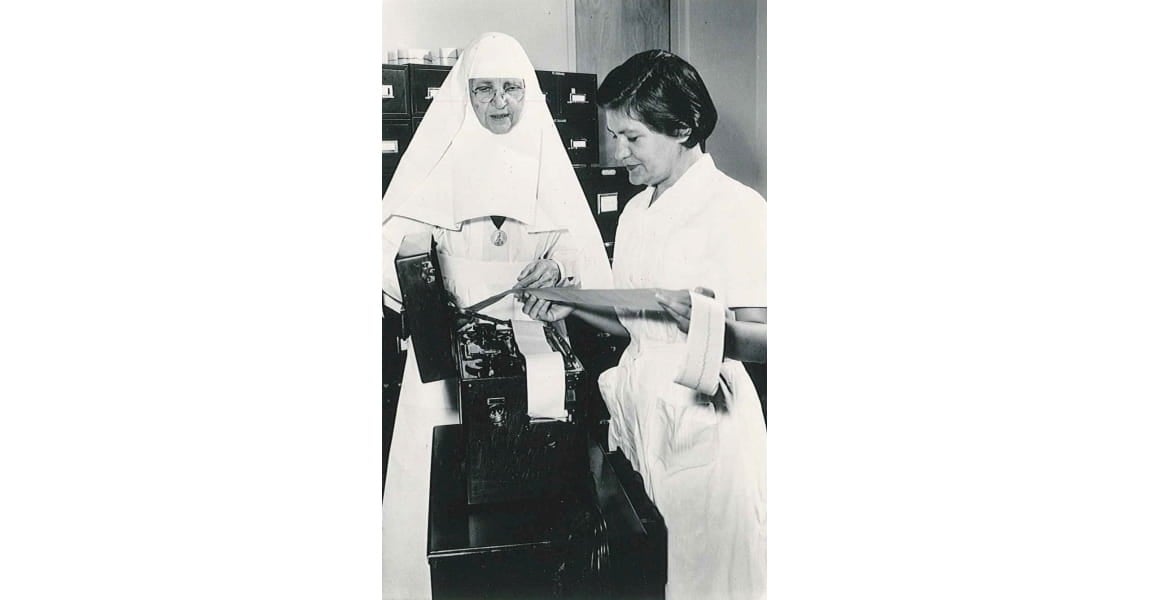 One of the Sister's of the Sorrowful Mother and alumni reading a cardiograph results