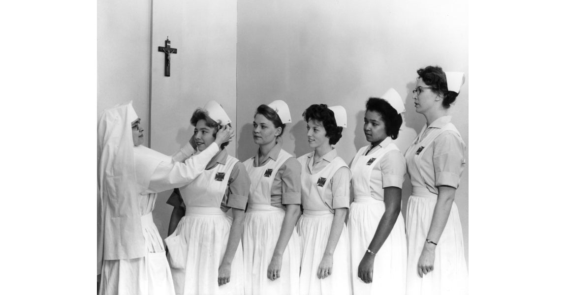 Sister fixing nurse's headwear