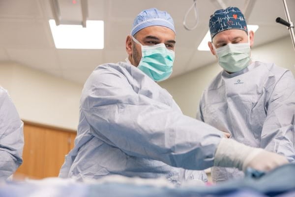 A surgical team wearing masks and gowns  preforms a surgical procedure on a patient