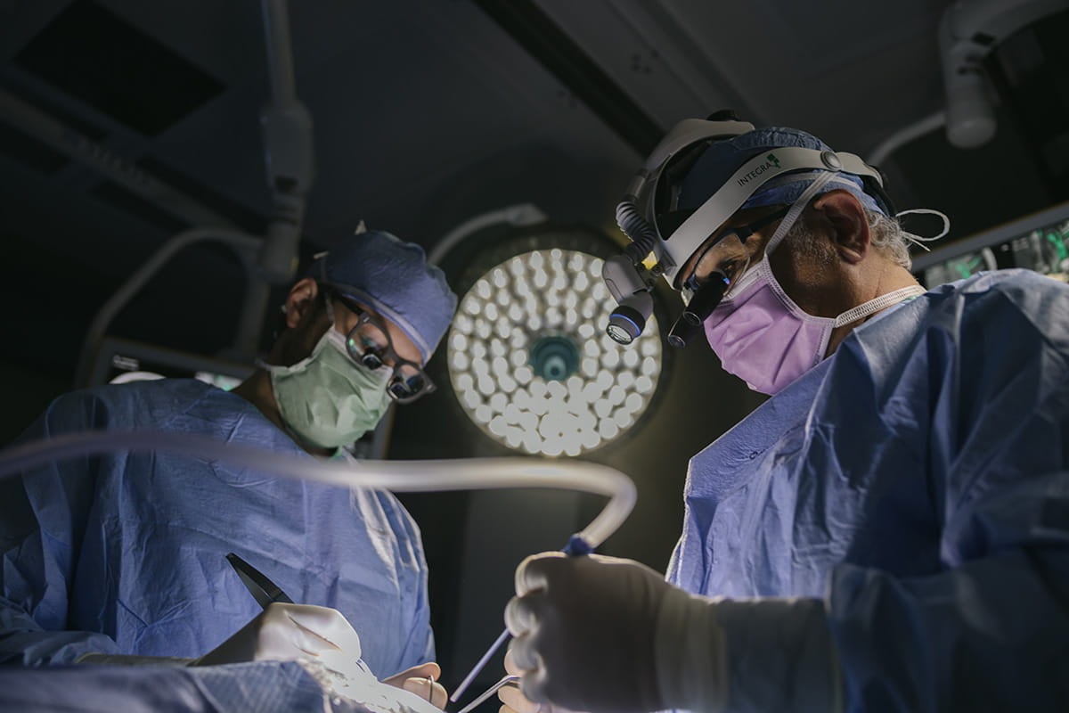 Two surgeons perform a procedure in an operating room.