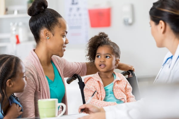 Woman with daughters speaks with her doctor.