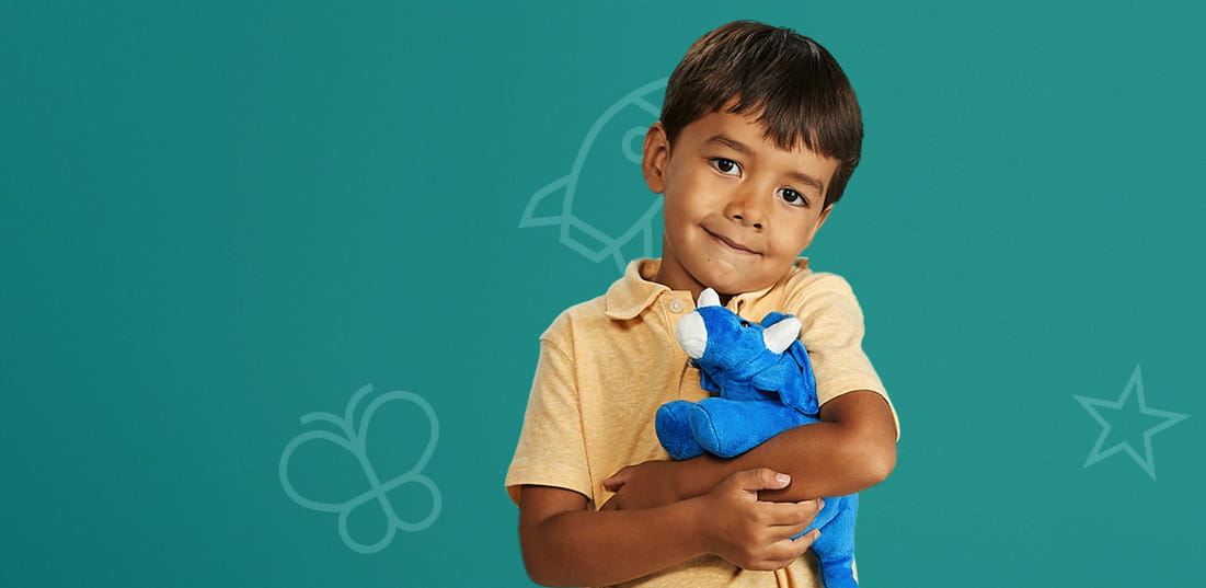 Young male patient at Dell Children's holding a blue stuff animal on a green background.