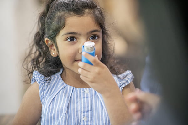 Young girl using inhaler getting care at Dell Children's.