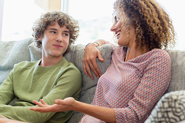 White teen boy talking with mother on couch.