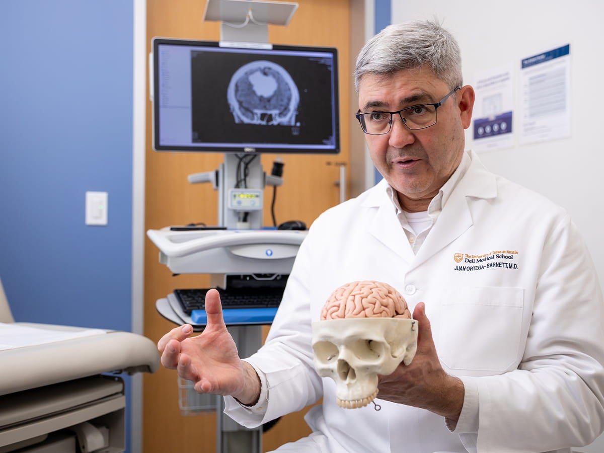 Seton Brain and Spine Institute neurosurgeon describes tumor care to patient in a clinic room. 