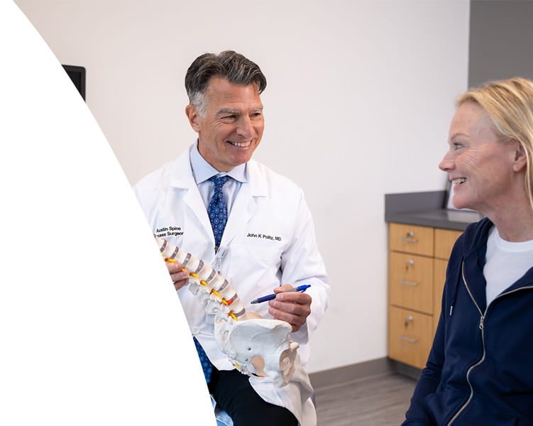 Spine surgeon shows a patient a model of the spine during an office visit.