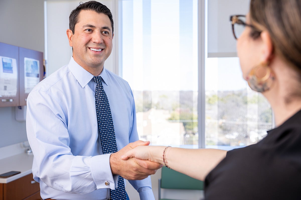 Dr. Joey Romero enters a patient room, greeting a patient.
