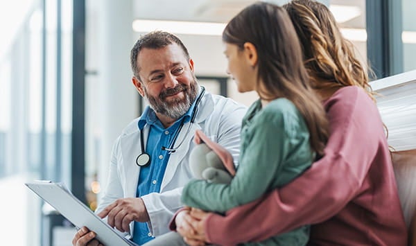 Male doctor talking with a mom and her daughter.