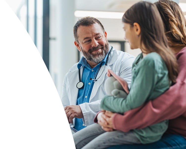 Male doctor talking with a mom and her daughter.