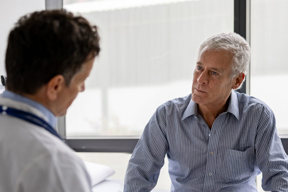 Younger male doctor talking to older male patient about heart surgery