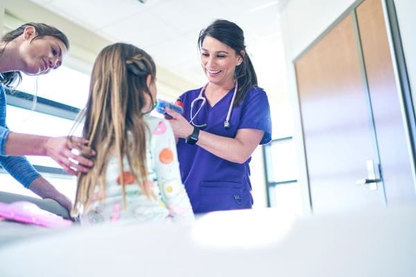 little girl receiving breathing treatment from female care provider