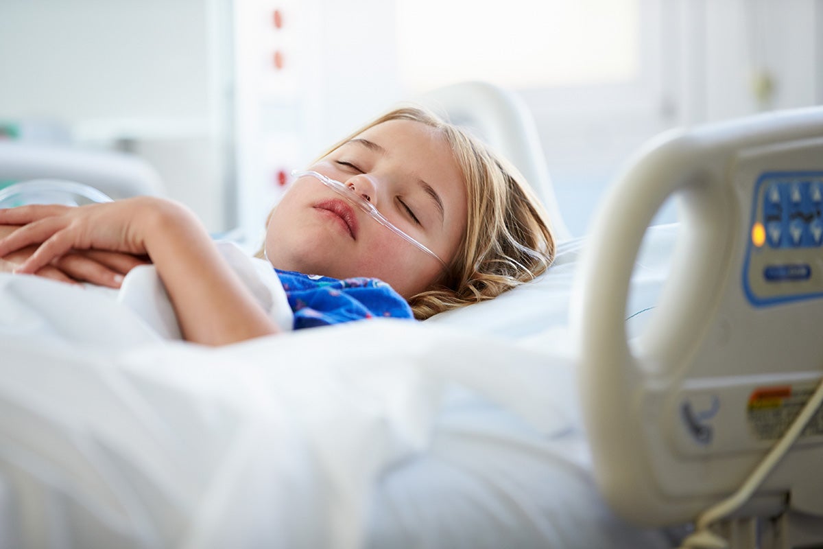 A young girl sleeping in a hospital bed.