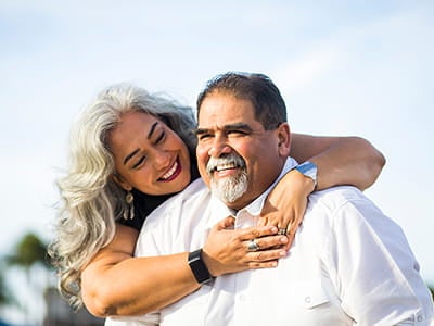 A woman is hugging a man. 