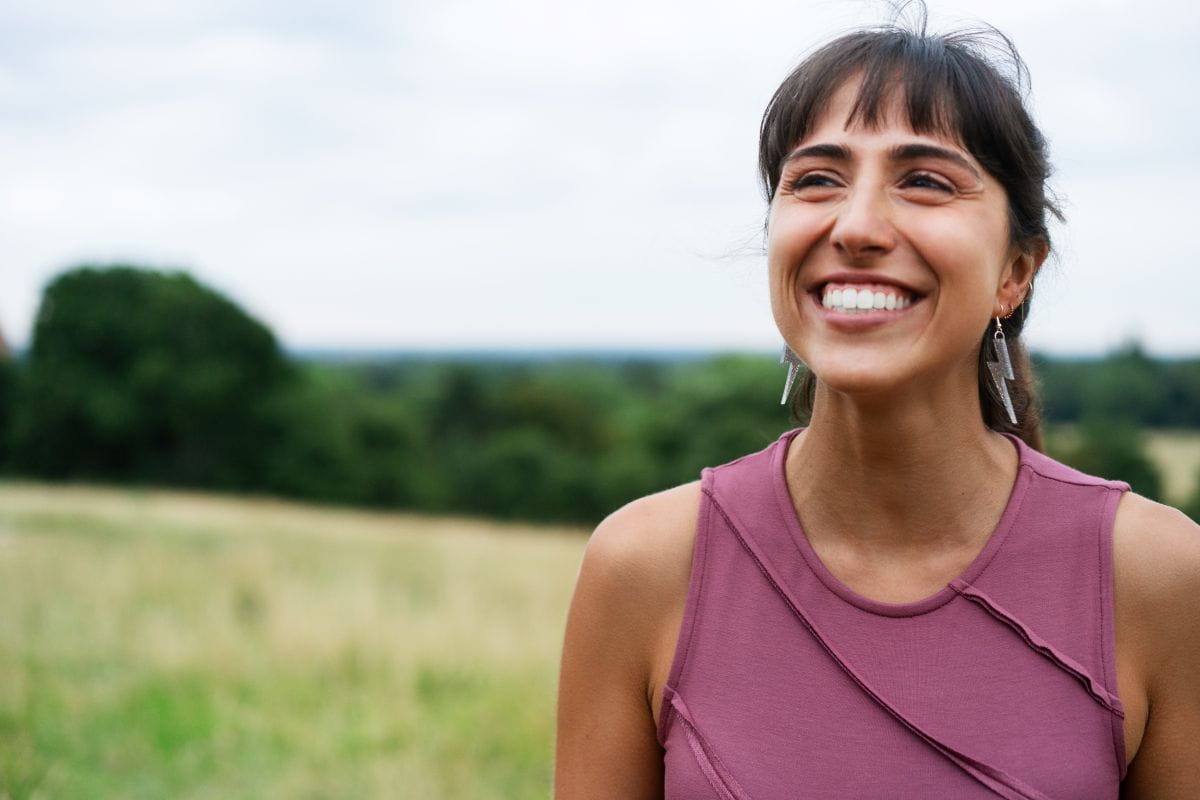 woman smiling  field with tree in background