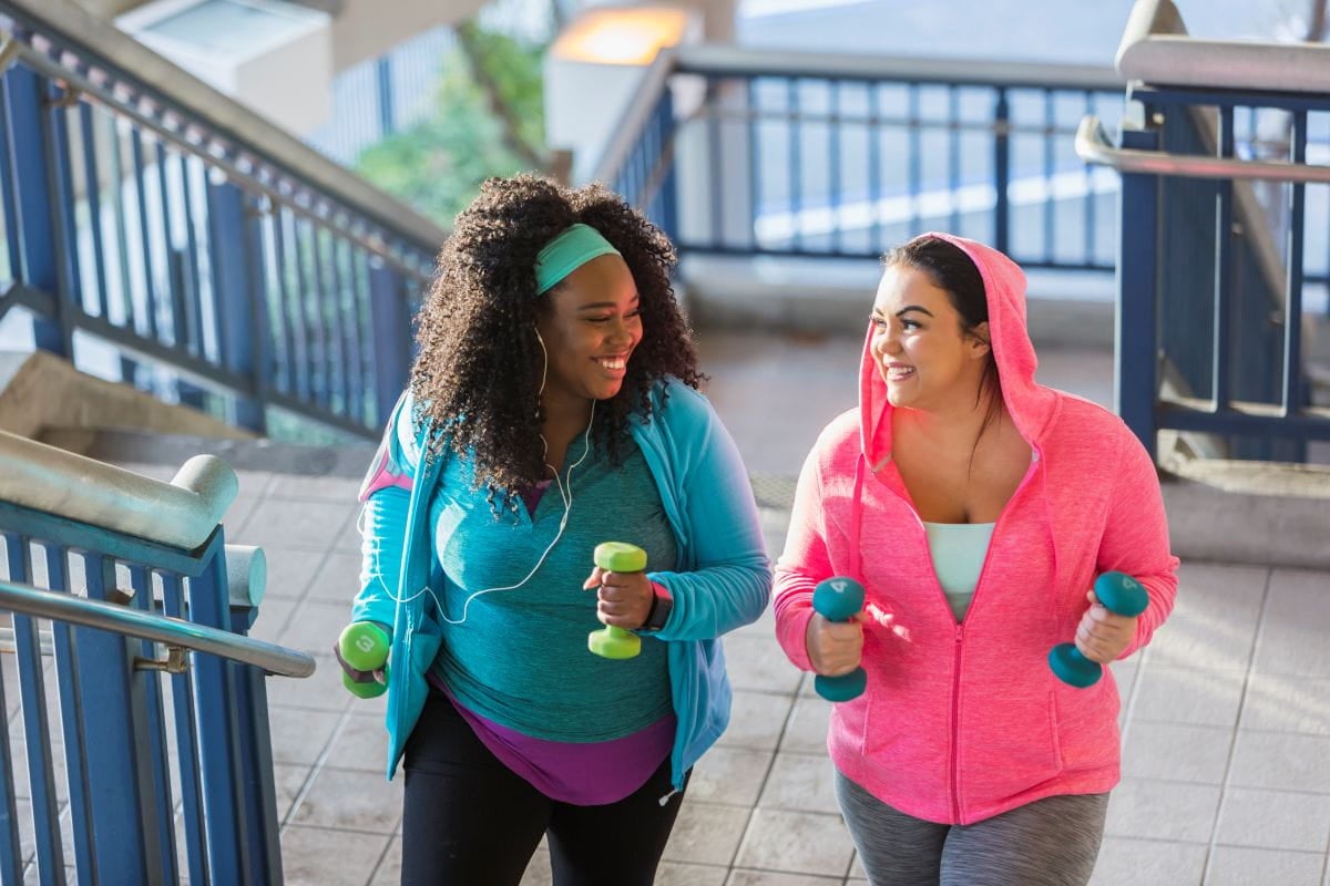 two women walking up stairs holding hand weights