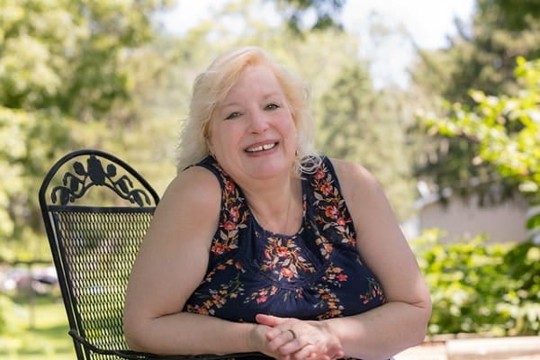woman sitting in chair in front of trees