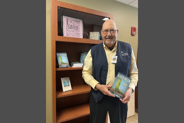 Curt Ghormley, Ascension Via Christi cancer patient, holding book he wrote.