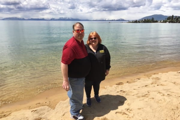 Married couple pose by the lake pre-bariatric surgeries.