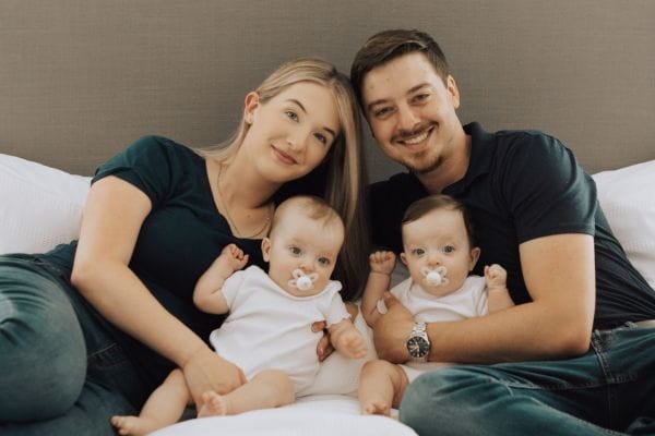 Maya Mendez, her husband, and their twin children posing on a bed