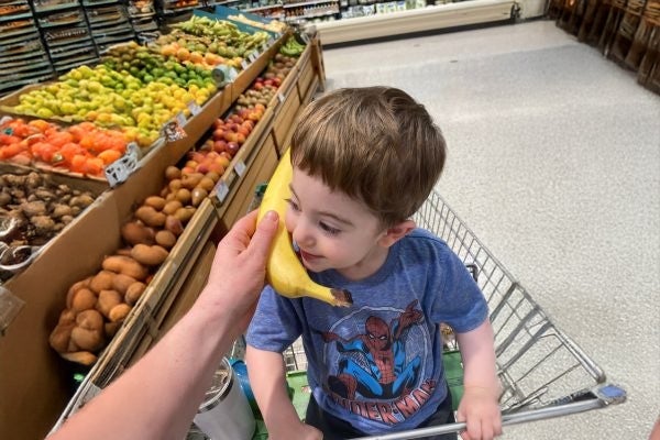Oryan sits in a shopping cart and plays with a banana