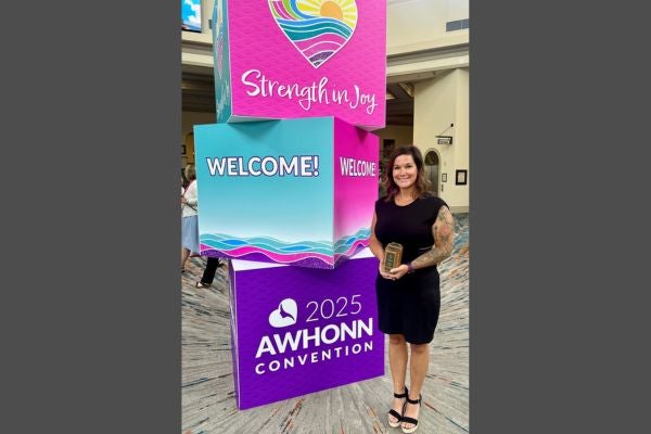 Miranda Wahnsiedler, MSN, BS, AGCNS-BC, RNC-OB, C-ONQS, holds her Award of Excellence in Practice awarded to her by the Association of Women’s Health, Obstetric and Neonatal Nurses