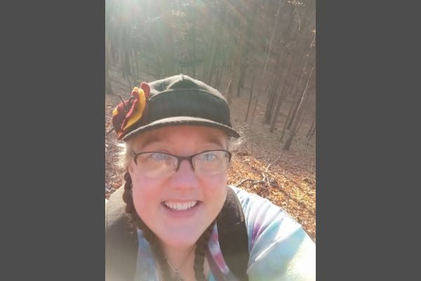 A middle aged woman takes a selfie in the woods during a fall hike.