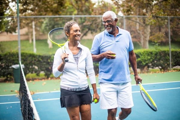 stock image of man and woman on tennis court holding tennis rackets