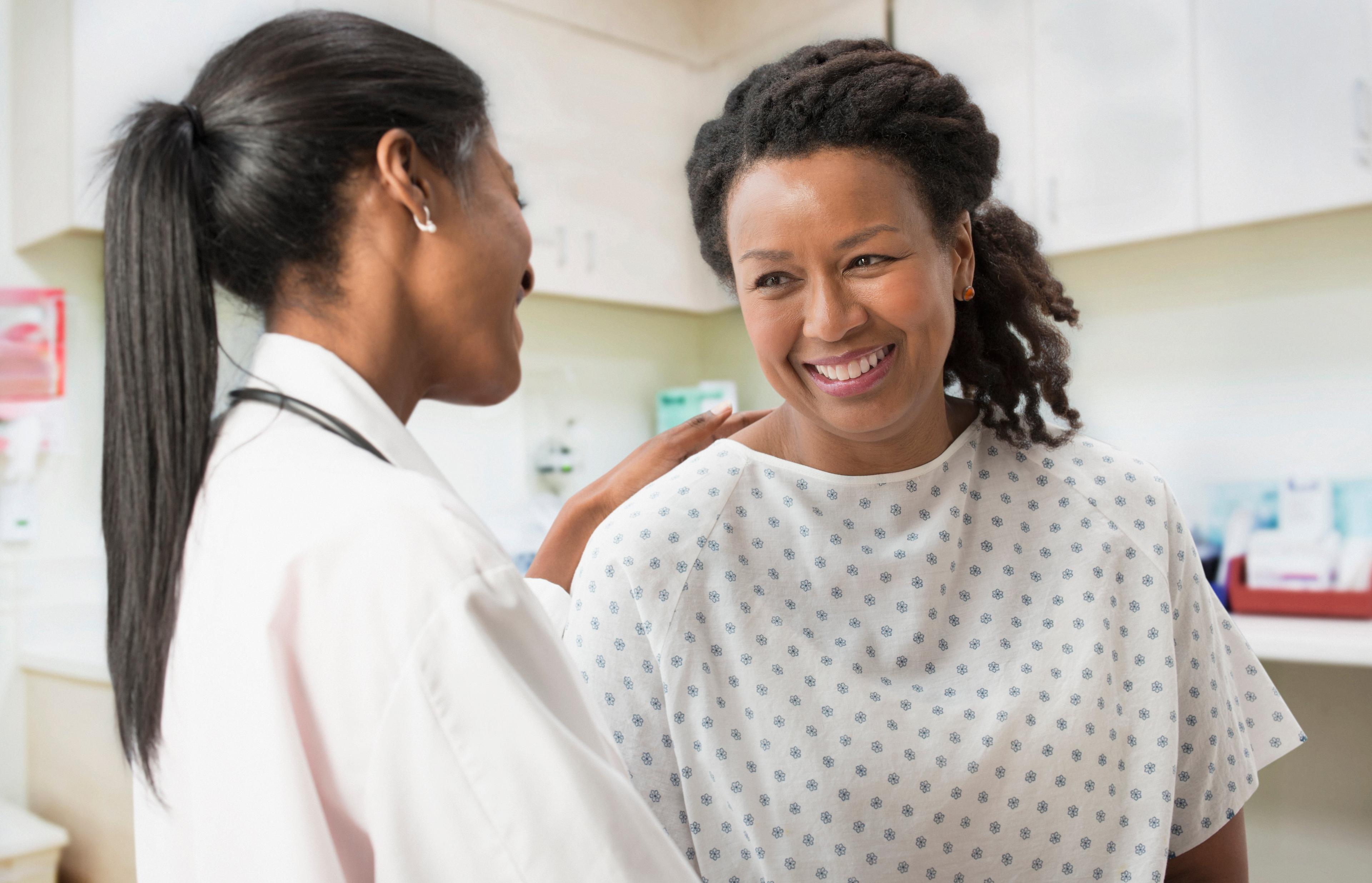 Doctor speaks with a smiling patient in a hospital examination room.