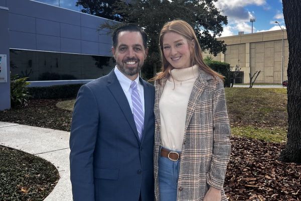 Dr. Martino standing outdoors beside a smiling woman in front of a medical building.