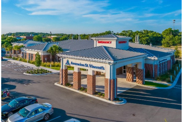Exterior view of Ascension St. Vincent’s Emergency Care – Arlington, featuring a covered entrance with brick columns, emergency signage, and a parking lot in front of the building.
