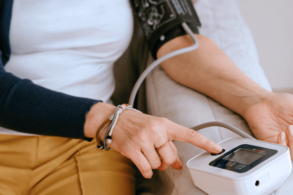 Person measuring blood pressure at home using a digital monitor on their arm.