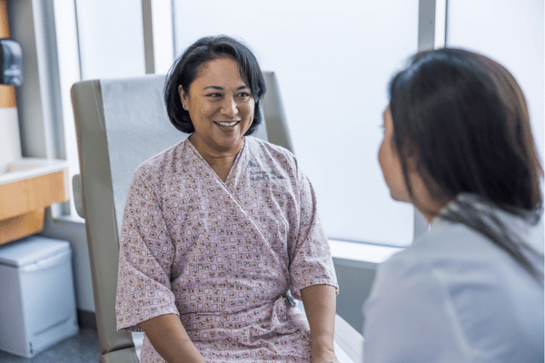 A patient sits with her doctor before receiving a Pap smear.