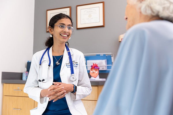 Priyanka Satish, MD, speaks with a patient in a clinic about their heart health.