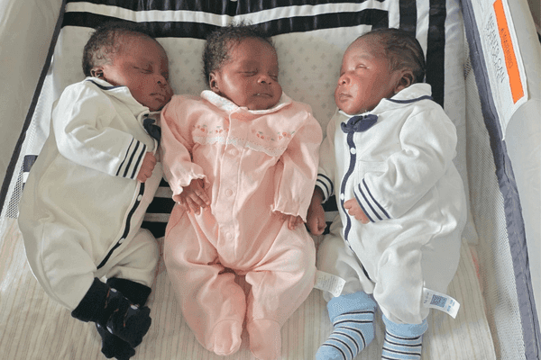 Triplets Osayui, Osayimwense and Osagiede Isokpunwu sleep side by side in a bassinet