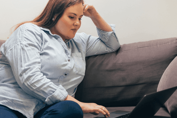 Person using a laptop while seated on a couch at home